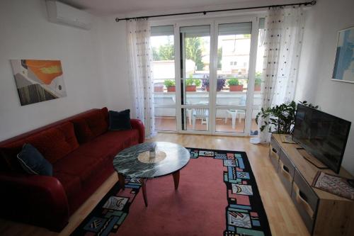 ein Wohnzimmer mit einem roten Sofa und einem Tisch in der Unterkunft Apartman Mak in Bihać