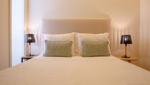 a white bed with two pillows and two lamps at GuestReady - Catorze de Outubro Houses 427 in Vila Nova de Gaia
