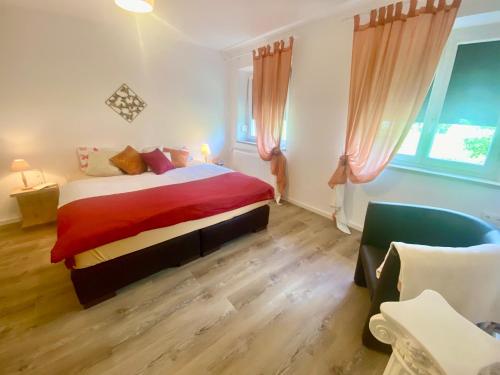 a bedroom with a bed with a red blanket and a chair at Ferienwohnung Altes Zollhaus in Ering