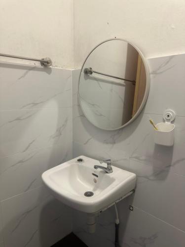 a white bathroom with a sink and a mirror at Jenny Homestay in Teluk Intan