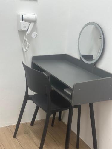 a black desk with a mirror and a chair at Jenny Homestay in Teluk Intan