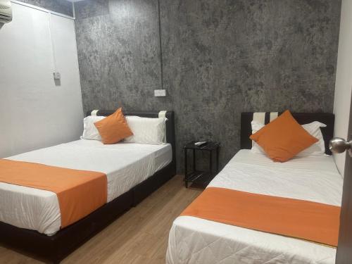 two beds with orange and white sheets in a room at Jenny Homestay in Teluk Intan