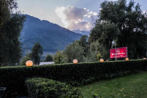 a sign in a field with a mountain in the background at Honeymoon Inn Manali in Manāli