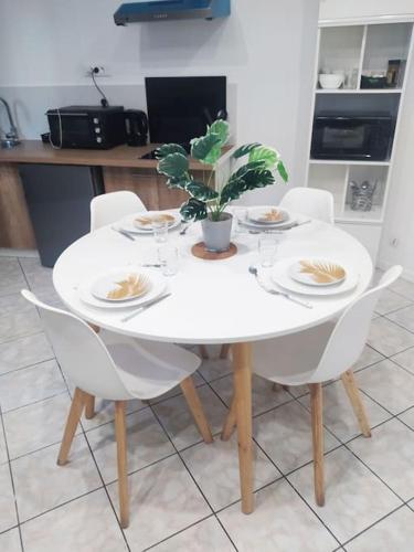 une table blanche avec des chaises, des assiettes et une plante dans l'établissement Studio Cosy au Calme, RER-2arrêts Stade-25minParis, à Stains