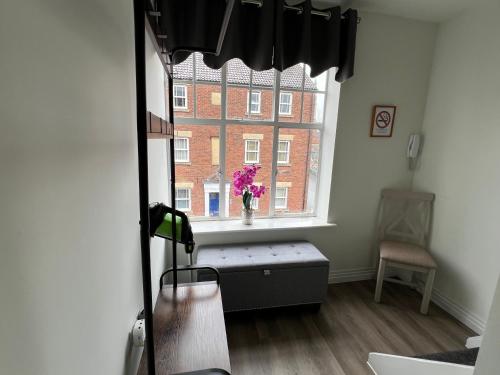 Cette chambre dispose d'une fenêtre avec un vase de fleurs. dans l'établissement Glastonbury Secret Retreat - 1 BD Split-Level Apt, Sleeps 3, à Glastonbury