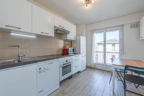 une cuisine avec des appareils blancs, une table et une fenêtre dans l'établissement M18 Marquer T3 proche gare d'Annemasse, à Annemasse