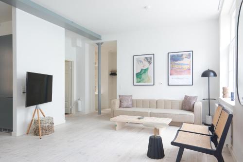 a white living room with a couch and a tv at Stylish Apartment in Heart of CPH near Strøget & the Canals in Copenhagen