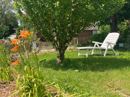 a white chair sitting in the grass next to a tree at Ferienwohnung Altes Zollhaus in Ering