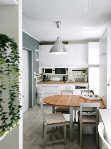 a kitchen with white cabinets and a wooden table and chairs at Apartment Astina in Koper