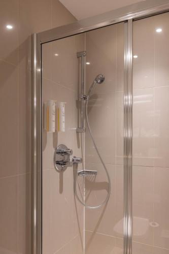 a shower with a glass door in a bathroom at Park Grand Hyde Park in London
