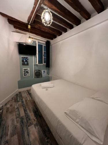une chambre avec un lit blanc et une fenêtre dans l'établissement Joli 2 pièces proche Marais, à Paris