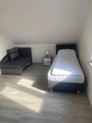a small bedroom with a bed and a couch at Biebrzańska Przystań 5 in Goniadz
