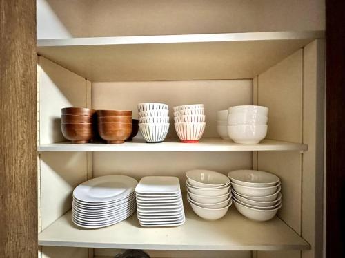a shelf filled with plates and bowls and bowls at 函館民泊イナンクル in Hakodate
