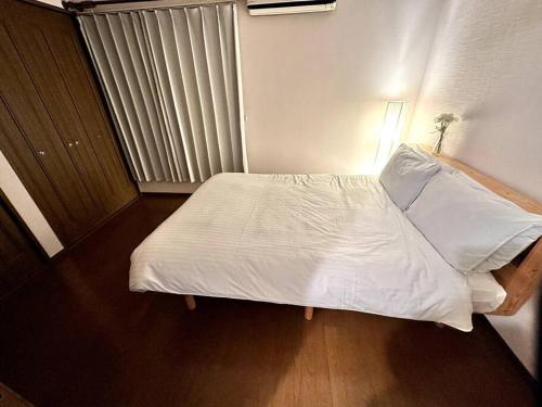 a small bedroom with a bed with white sheets at 函館民泊イナンクル in Hakodate