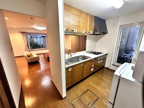 a kitchen with wooden cabinets and a living room at 函館民泊イナンクル in Hakodate