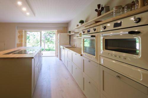 une grande cuisine avec des placards blancs et un four dans l'établissement La Maison de Jennie, à Saint-André-dʼAllas