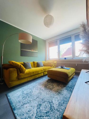 a living room with a yellow couch and a rug at Ferienwohnung Hafennest 15206 in Leer