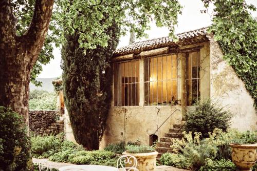a stone house with a window and a tree at Le Galinier Lourmarin, a Beaumier Guesthouse in Lourmarin