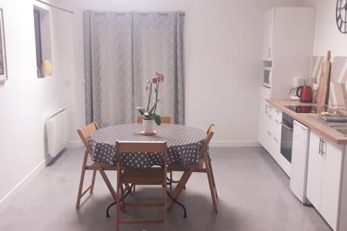 a kitchen with a table with a vase of flowers on it at Entre Loire et Vignes in Juigné-sur-Loire