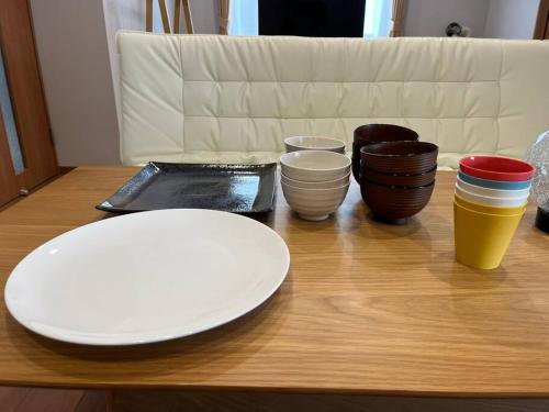 a wooden table with plates and bowls on it at Peaks Home101 in Higashikawa