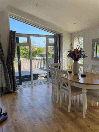 a dining room table with chairs and a vase with flowers at Ebba Lodge in Eyemouth