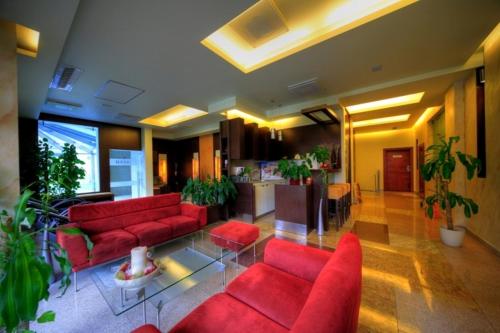 Avangard Resort في سفينويتشي: غرفة معيشة مع الأرائك الحمراء والنباتات الفخارية
