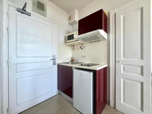 une petite cuisine avec une porte blanche et un évier dans l'établissement Résidence LES CALANQUES route des sanguinaires- Piscine - Parking & Wifi Gratuit - Plage, à Ajaccio