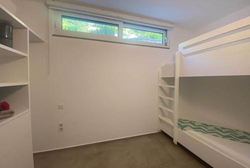 a white room with a window and a shelf at Dreamscape Villa Oneiro - Your Gateway to Seaside in Évyiros