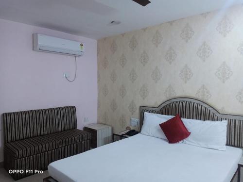 a bed and a chair in a room with a bed and a pillow at Hotel Ambassador Inn in Gwalior