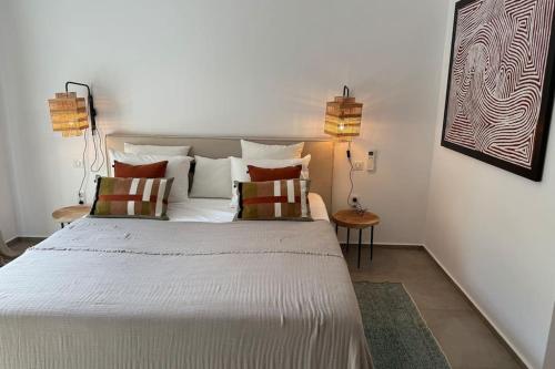 a bedroom with a large white bed with two lamps at Dreamscape Villa Oneiro - Your Gateway to Seaside in Évyiros