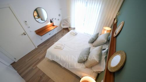 a bedroom with a white bed and a mirror at Luminara Villa in Santa Luzia