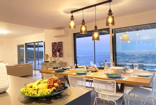 a dining room with a table with a bowl of fruit at Dreamscape Villa Oneiro - Your Gateway to Seaside in Évyiros