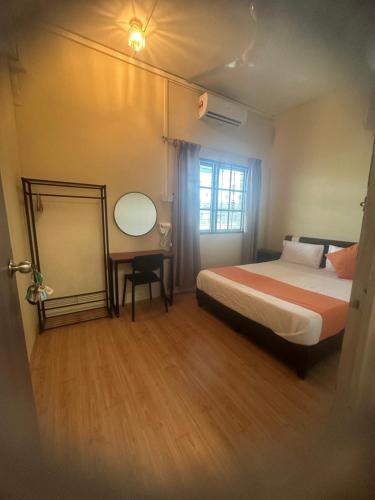 a hotel room with a bed and a desk and a window at Jenny Homestay in Teluk Intan