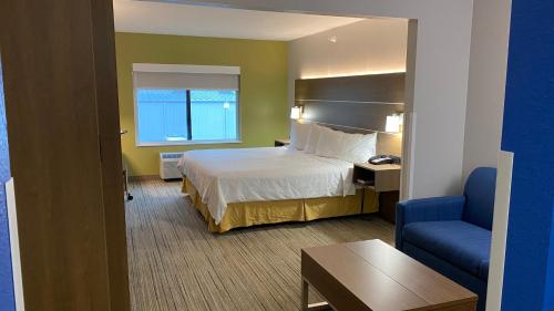 a hotel room with a bed and a blue chair at Holiday Inn Express Hotel & Suites Weston by IHG in Weston