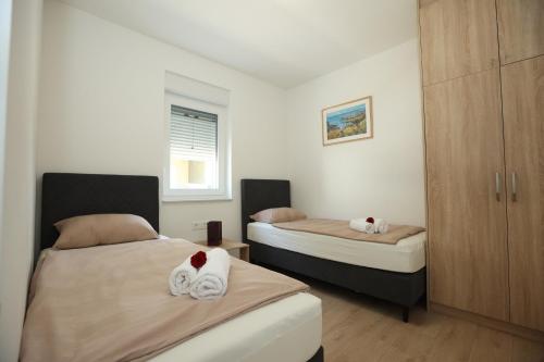 a bedroom with two beds with towels on them at Sea&Sand Apartment - Modern Sea View near Sandy Beaches in Privlaka
