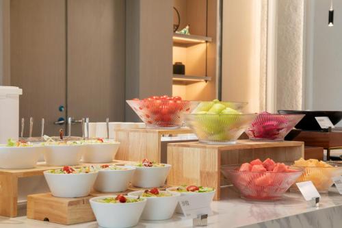 Un buffet lleno de tazones de frutas y verduras en Atour Hotel Shanghai Baoshan Shangda Road, en Shanghái