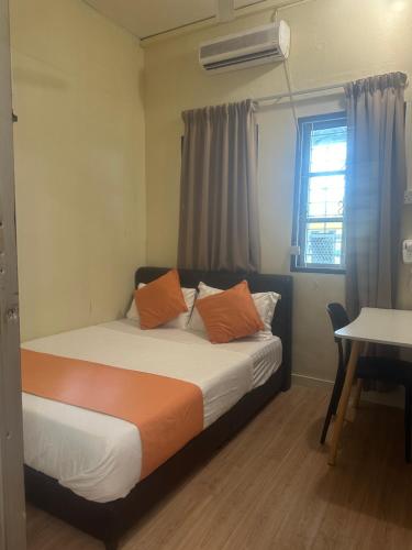 a bedroom with a bed with orange pillows and a window at Jenny Homestay in Teluk Intan