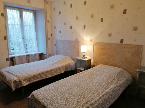 Un dormitorio con dos camas y una lámpara sobre una mesa. en gite Le verger de la Faverie, en Saint-Nicolas-des-Bois