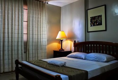 a bedroom with a bed with a lamp and a window at Metro Vigan Inn in Vigan