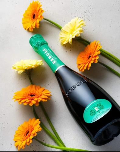 a bottle of wine next to flowers on a table at Antica Rinaldo in Valdobbiadene