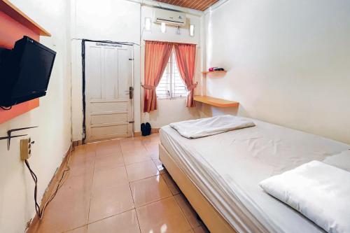 a small bedroom with a bed and a television at Amira House Kisaran RedPartner in Kisaran