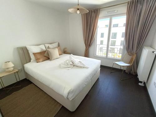 une chambre avec un grand lit blanc et une fenêtre dans l'établissement Disney T3 LUXE neuf 6P 2 ch 2 salle de bains parking privé en sous sol lit bébé C205, à Chessy