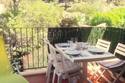 une table blanche avec des chaises et des verres sur un balcon dans l'établissement Cap Soleil studio 4 pers piscines, tennis, mer, à Saint-Mandrier-sur-Mer