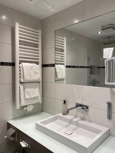 a white bathroom with a sink and a mirror at Landhaus Alpinia in Berlin