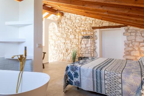 a bedroom with a bed and a bath tub and a stone wall at Las Casitas Del Mar in Alicante