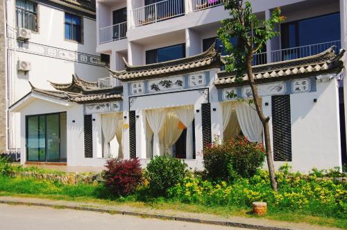a white building with a tree in front of it at Dali Fish Inn Sea View Hotel in Dali