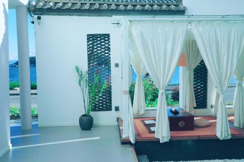 a bedroom with white curtains and a large window at Dali Fish Inn Sea View Hotel in Dali