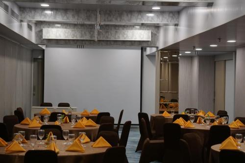 a conference room with tables and chairs and a screen at Unisi Hotel Malioboro - Jogja Syariah in Yogyakarta