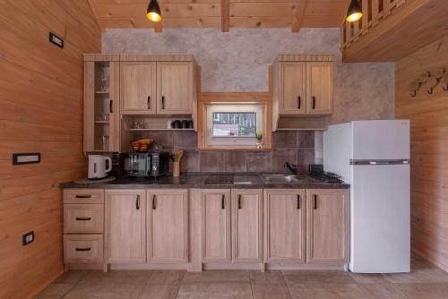 a kitchen with wooden cabinets and a white refrigerator at Resort pri Hrastu in Kamnik