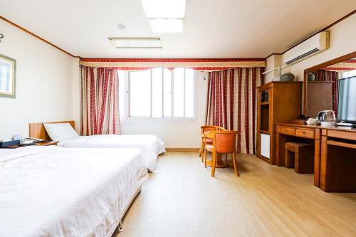 チョンジュにあるNewvera Hotelのベッド2台と机があるホテルの部屋